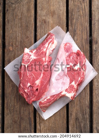 Two raw fresh meat steak on wooden board, selective focus