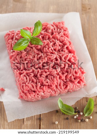 Minced meat on butcher paper with basil and pepper, selective focus