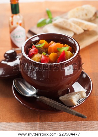 Hot goulash soup in pot with slice of bread, selective focus