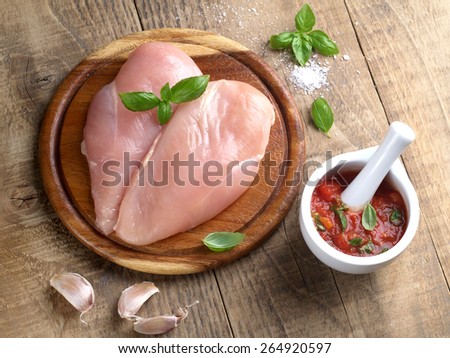 Raw chicken breast on a wooden table with sauce or marinate, selective focus