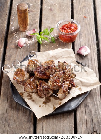 Grilled meat (kebab) with sauce on wooden background, selective focus