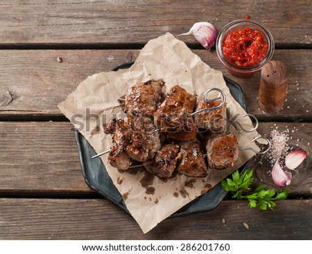 Grilled meat (kebab) with sauce on wooden background, selective focus