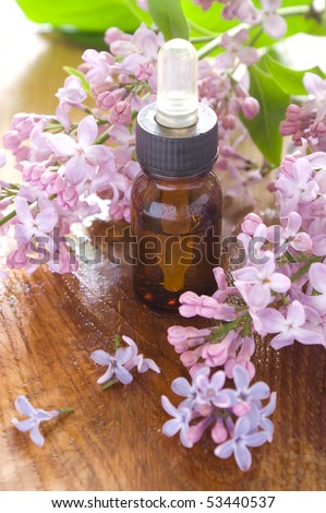 Essential oil bottle with lilac in background