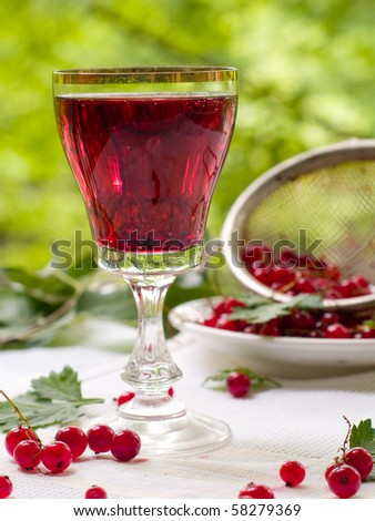Red fruit wine in wineglass with red currants