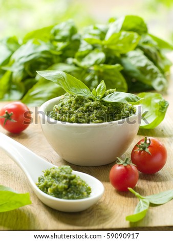 Basil pesto in a small bowl, with fresh basil leaves.