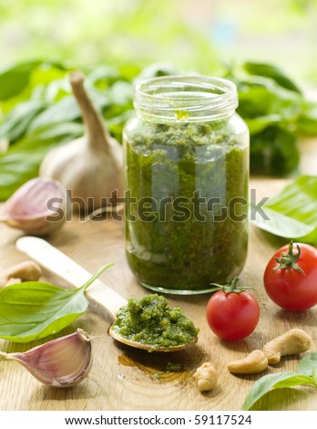 Basil pesto in a spoon, with fresh basil leaves.