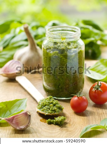 Basil pesto in a spoon, with fresh basil leaves.