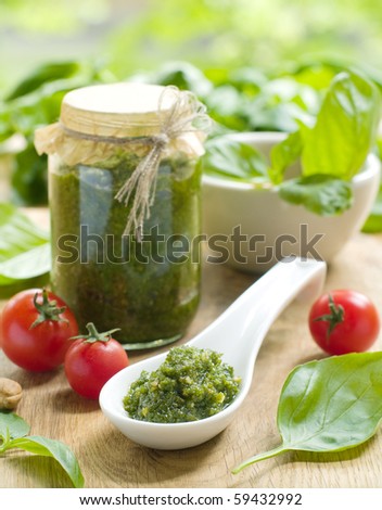 Basil pesto in a ceramic spoon, with fresh basil leaves.