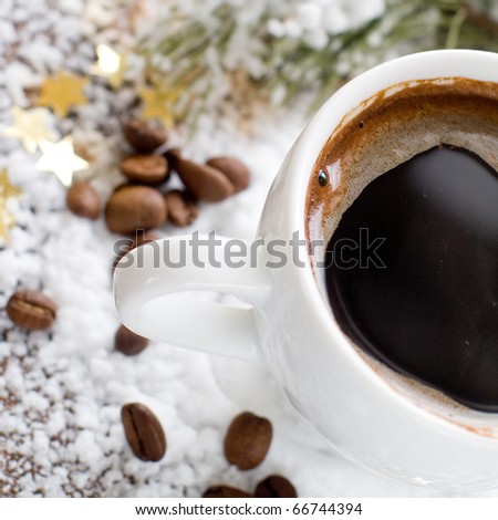 Cup of espresso coffee in snow with beans