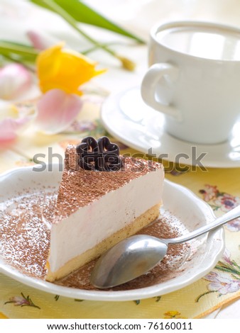 Cheesecake with fresh coffee and flower on background
