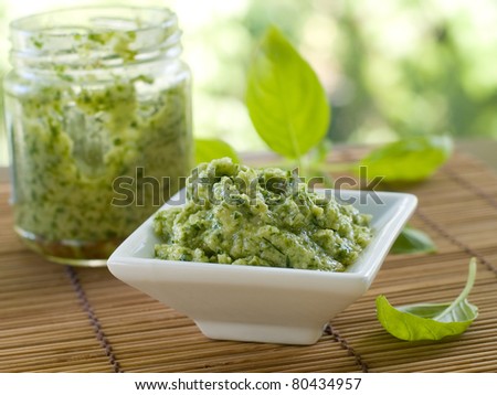 Basil pesto in a small bowl, with fresh basil leaves. Selective focus, shallow doff