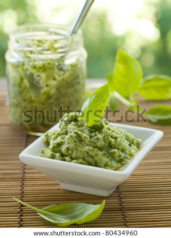 Basil pesto in a small bowl, with fresh basil leaves. Selective focus, shallow doff