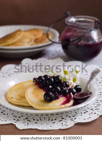 pancakes with black currant jam topping on plate with fork. Selective focus
