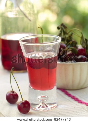 Cherry liquor in glass on natural background. Selective focus