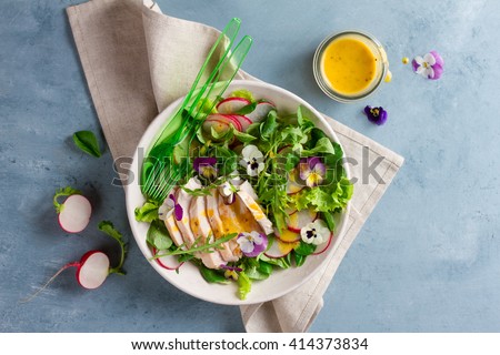 Spring salad with radishes, chicken breast and edible flower, selective focus