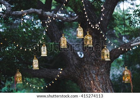 Night wedding ceremony with a lot of candles and vintage lamps on big tree