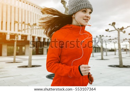Portrait of young female runner jogging in the city park. Joyful face, successful smile, dynamic hairs