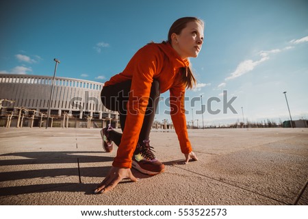 Sportswoman in ready position to run.Girl on the knee, preparing to start jogging.Achievements and goals