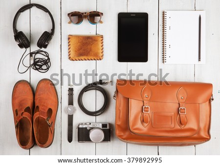 Travel concept - tablet pc, headphones, camera, shoes, watch and bag on the desk