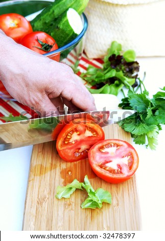  hand cuts ripe red tomatoes for summer healthy vegetable salad on a
