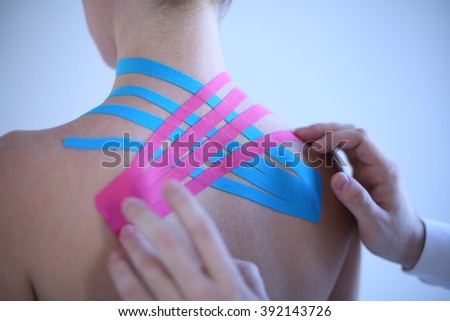 man reaches athletic sports tape on the back of a girl