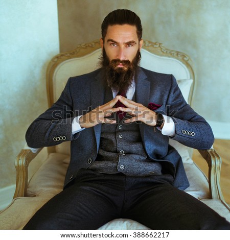 Handsome confident bearded man sitting in luxury white chair