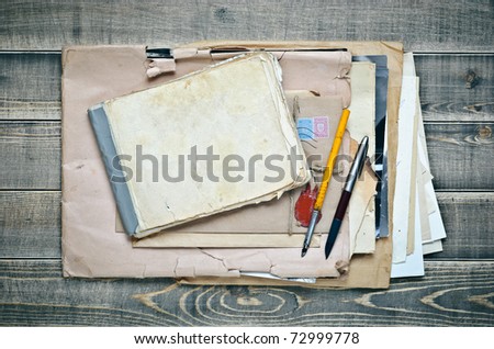 old notebook, envelope with paper and pens on a wooden table