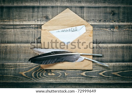 Vintage postal Envelope with paper and quill pen a on dark wooden planks background