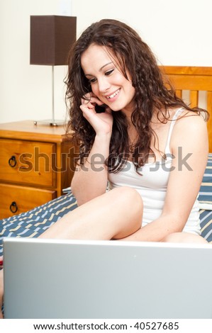teenage girl in bedroom surfing the net while chatting on the phone