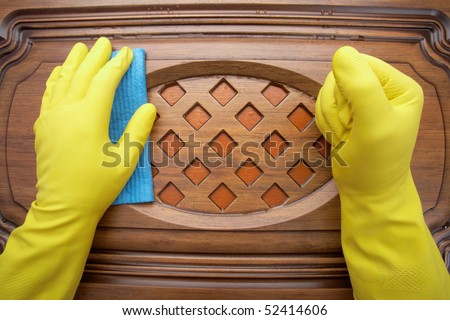Hands in yellow gloves with sponge, washing wooden surface