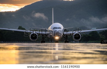 The commercial airplane standing on the airport taxiway or apron at sunset with blue sky background. Passenger airplane landing or taking off. Airplane concept.