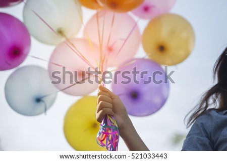 Beautiful woman holding balloons, colorful of multicolored balloons floating in the sky.