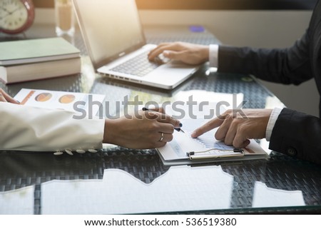Businessman pointed a finger at the paper,annual report,boss pointing on mistakes at office,notebook on table.He is using a laptop while on the job.
