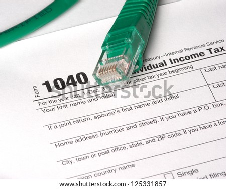 E-File Taxes - A 1040 tax form and network cable. Electronic Filing (E-File) concepts. The year on the form is hidden by the network cable to add to the image usefulness.