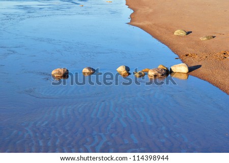Row of stones  in the freezing water of the Bay in autumn