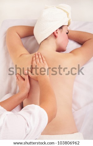 Image of therapist doing massage on female shoulder in salon