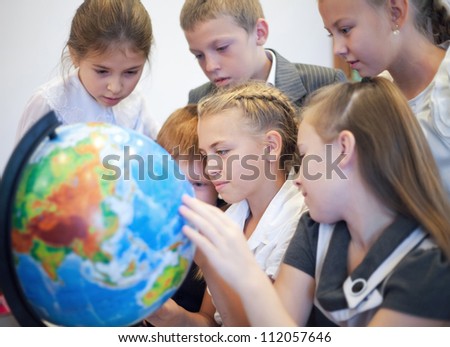 Happy schoolchildrensearching country on the globe