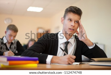 Young pensive student sitting at the table during examination