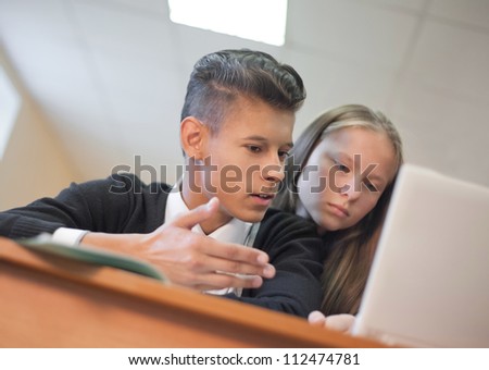 Down view of two  students chatting  and looking at laptop