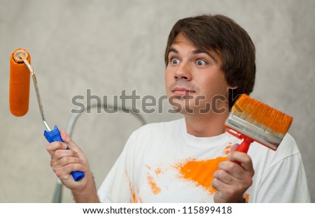 Surprised man holding paintbrushes and showing confuse