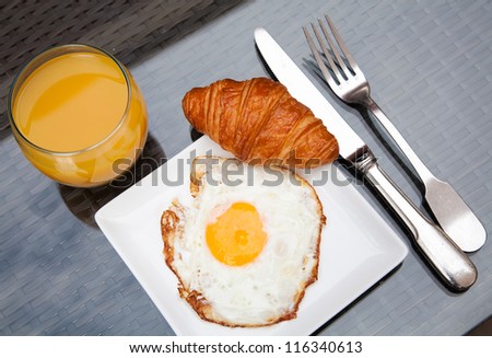 Fried eggs with croissant and juice