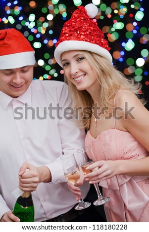Handsome man opening bottle of champagne and  girlfriend  near by