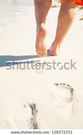 Man walks alone on beach, his feet and legs showing