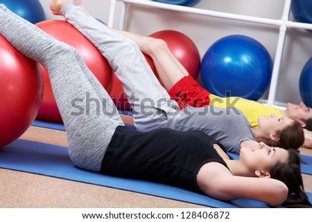 Row of people lying on mates with legs on balls