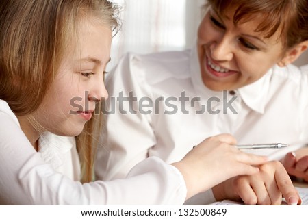 A smiling woman teach a cute girl