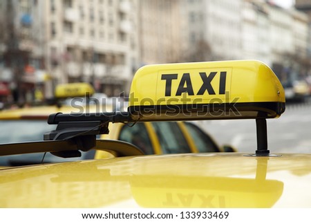 Taxi sign on a yellow car on urban street
