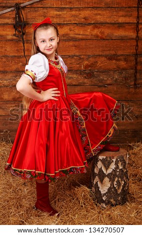 Smiling girl in Russian costume puts her leg on log