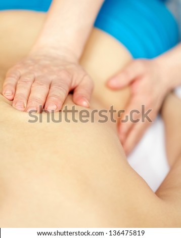 Therapist hands doing spa massage on female back