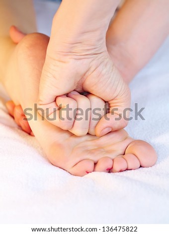 Therapist pressing by fist on foot while massage