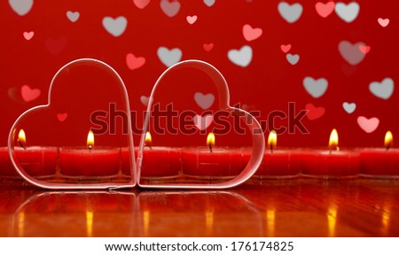 Two metal hearts on the background of  burning candles with hearts